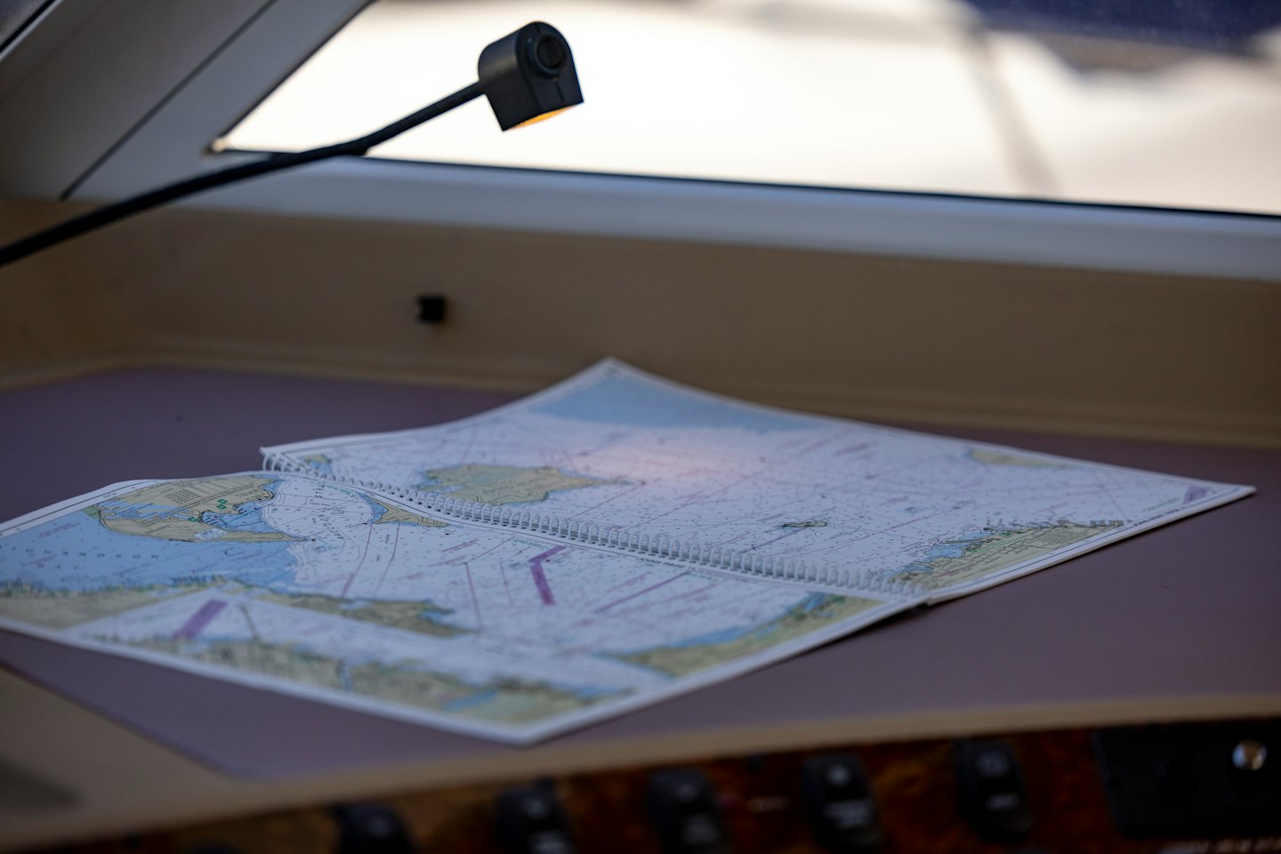 An open nautical chart lies on a wooden boat table.