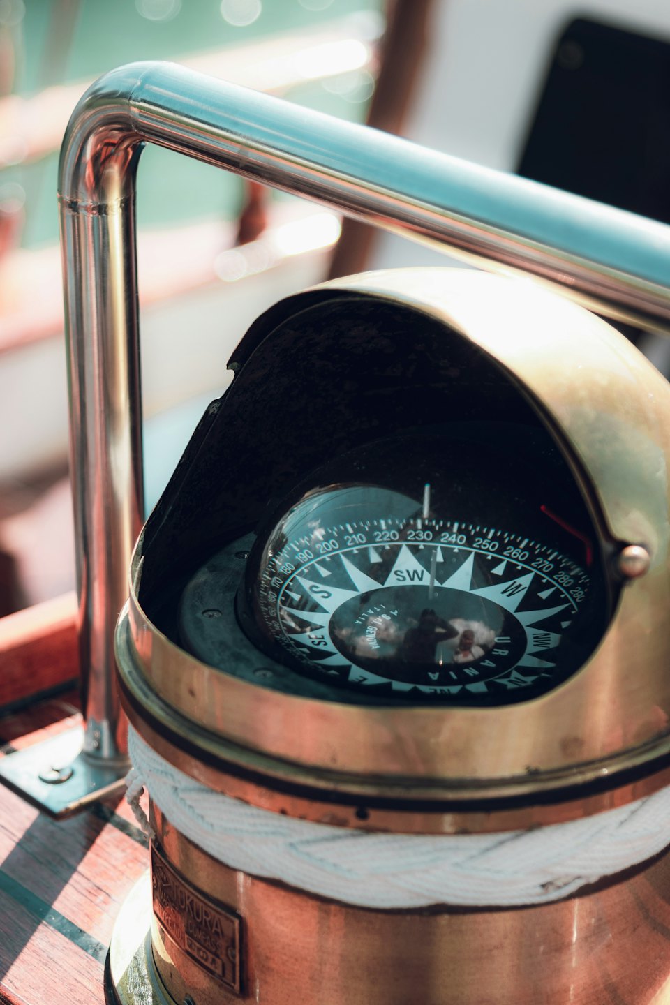 A brass marine compass sits on a wooden boat deck.