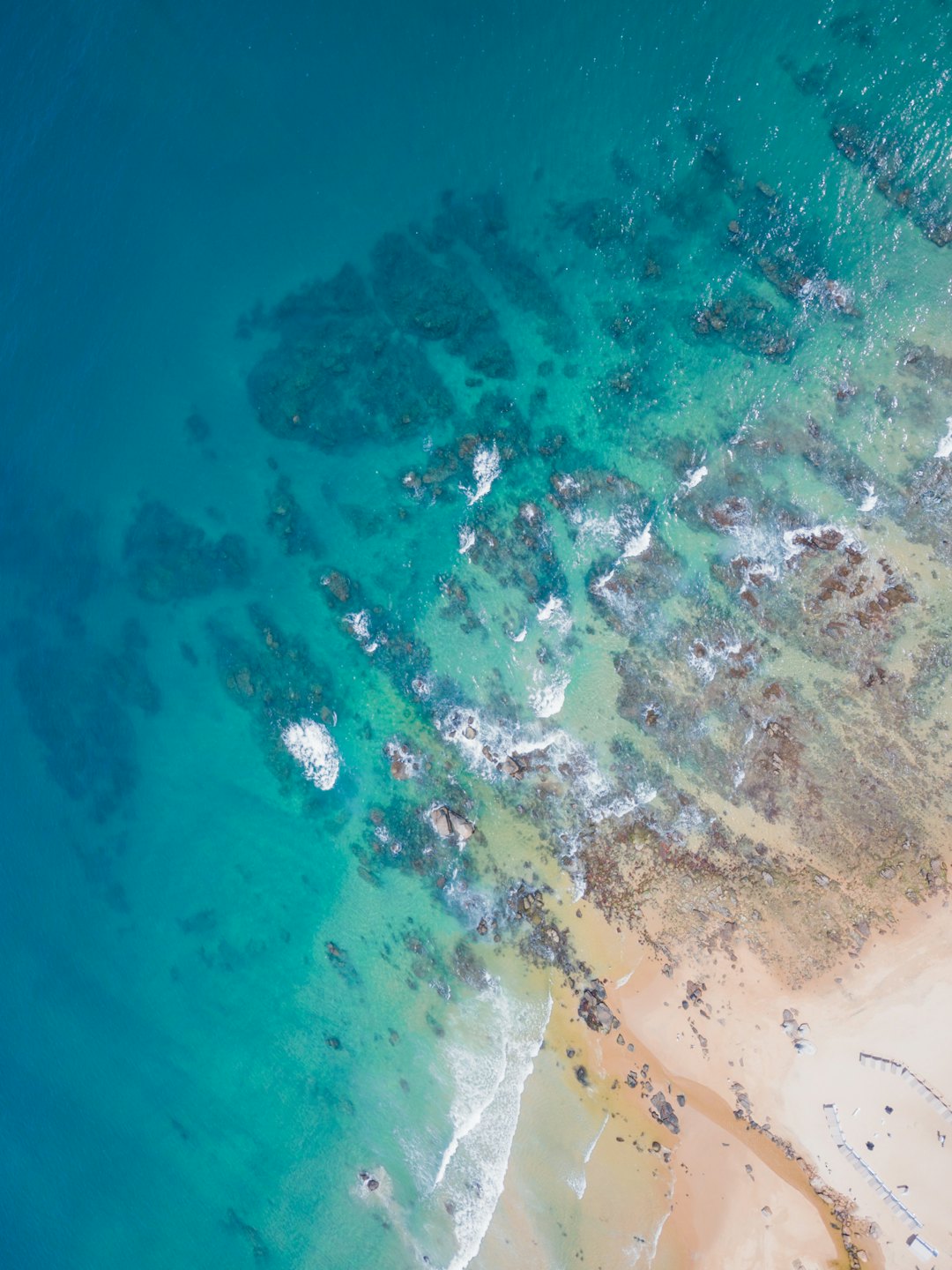 Blue ocean meets sandy beach with gentle white waves.
