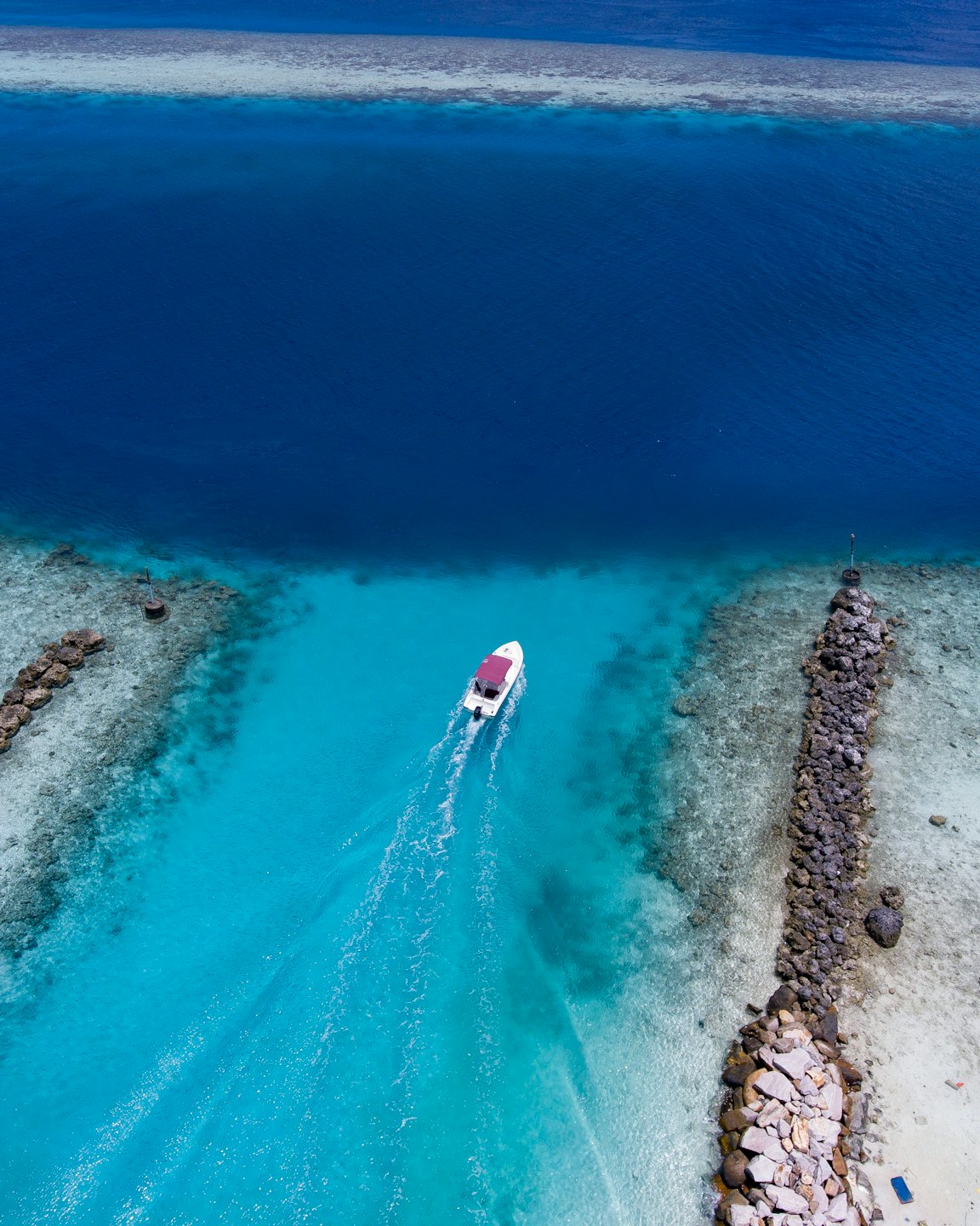 White boat with red canopy cruises through turquoise water channel.